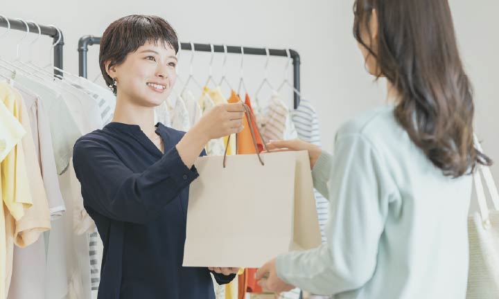 洋服店で店員から品物を受け取る女性
