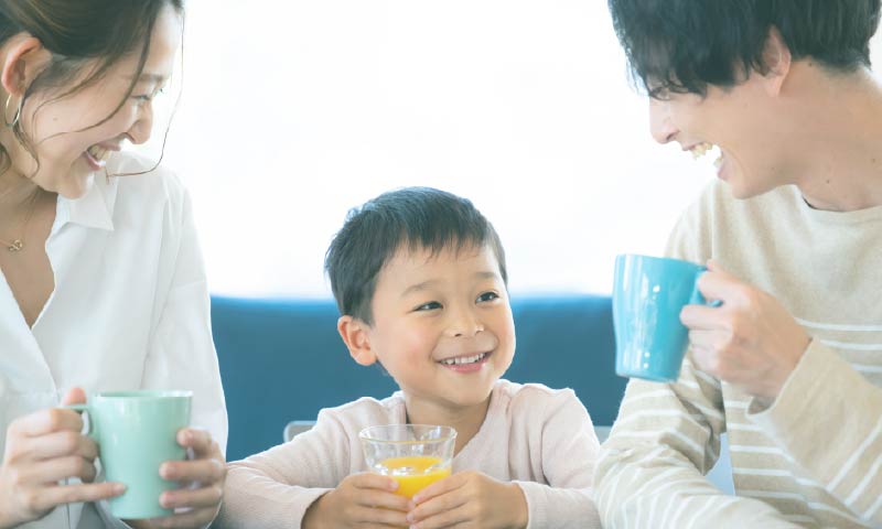 笑顔で飲み物を飲んでいる３人家族