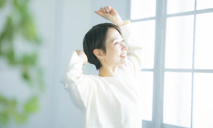 窓越しに日光を浴びる女性
